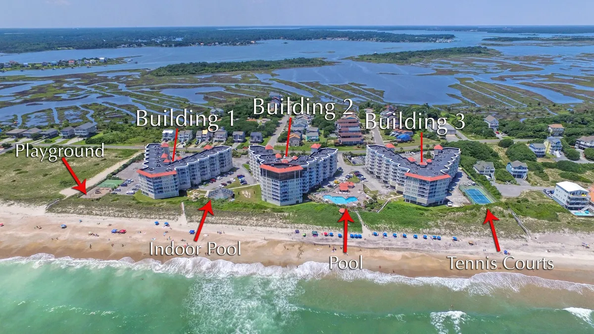 This exterior image showcases the St Regis property with clear views of the pool, playground, tennis courts, and the beach in the background. The overall scene is vibrant and family-friendly, encapsulating both the recreational amenities and the close proximity to the shore.