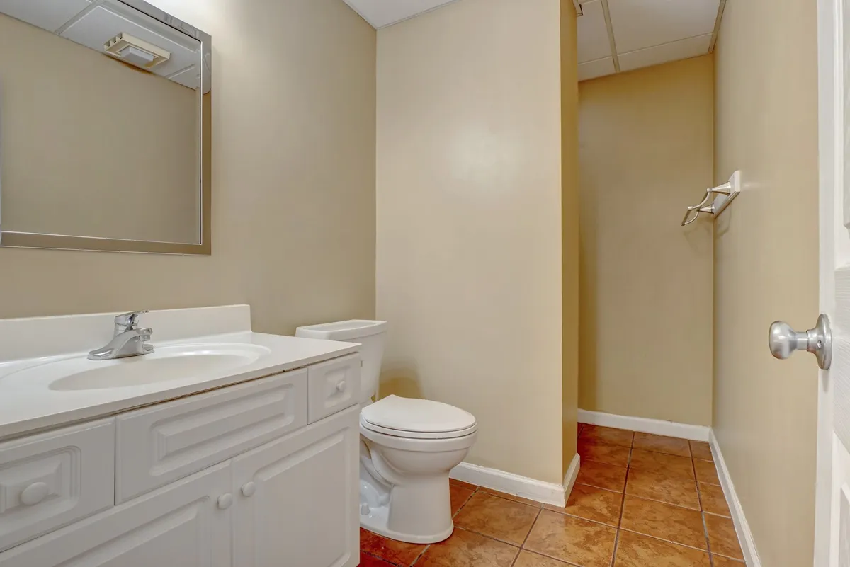 A bright, functional ensuite bathroom with a vanity sink, large mirror, and toilet. The simplistic yet clean design ensures both comfort and convenience for guests.