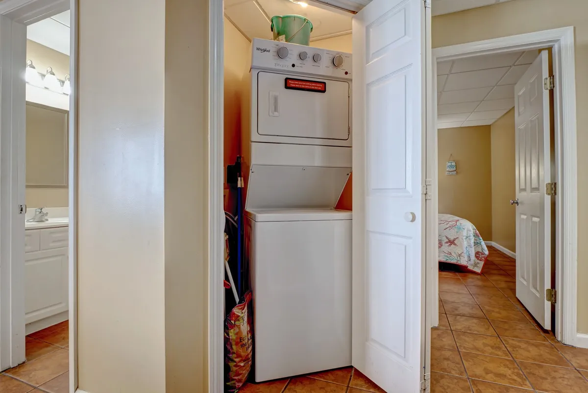 A hallway laundry area with a washer and dryer and doorways leading to other rooms. The space feels practical and welcoming, suggesting convenience for handling sandy towels and laundry after beach or pool activities.